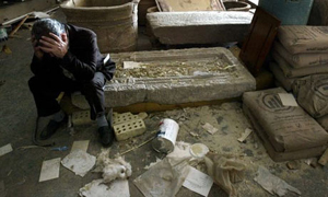 Mushin Hasan, the deputy director of the National Museum of Iraq, sits on artifacts detroyed following the looting in April 2003